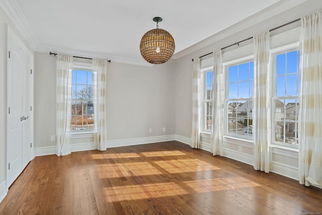 unfurnished dining area featuring crown molding, baseboards, and wood finished floors