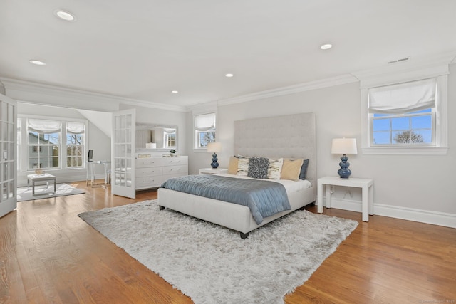 bedroom featuring french doors, crown molding, visible vents, wood finished floors, and baseboards