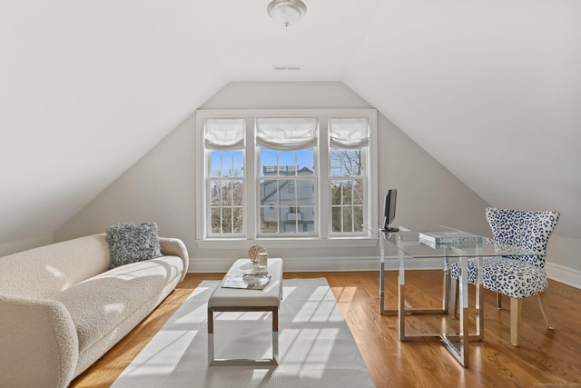 interior space with visible vents, vaulted ceiling, baseboards, and wood finished floors