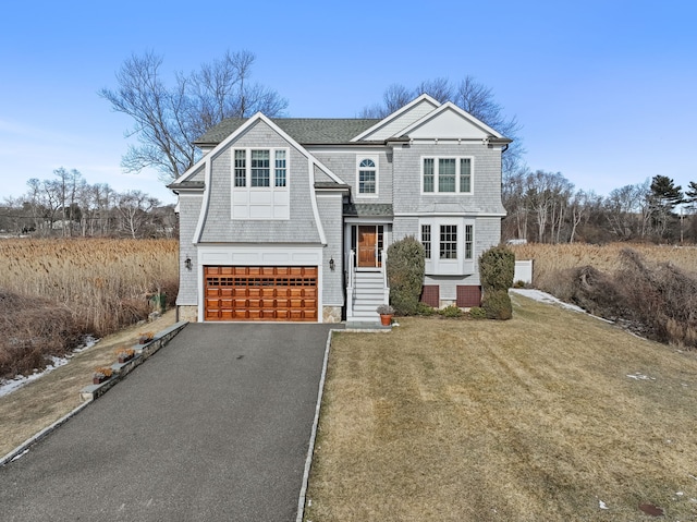 shingle-style home featuring a garage, driveway, and a front lawn