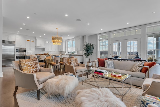 living room with an inviting chandelier, light wood-type flooring, and french doors