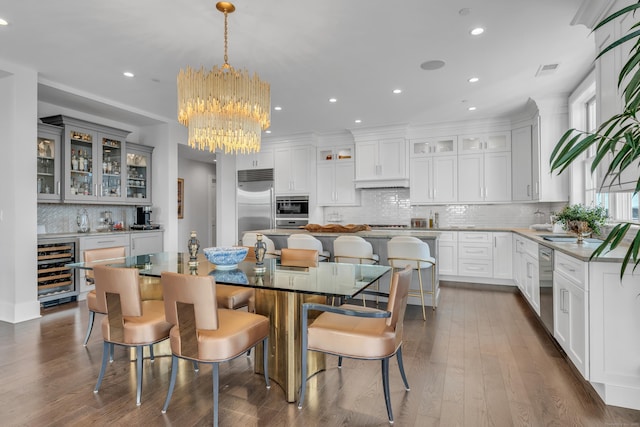 dining area with wine cooler, indoor bar, a chandelier, and dark wood-type flooring