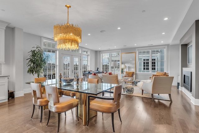 dining area with an inviting chandelier, wood-type flooring, and french doors