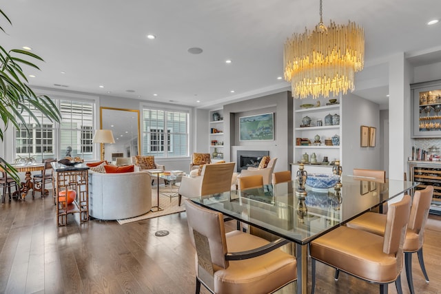 dining room with an inviting chandelier, built in shelves, and dark wood-type flooring