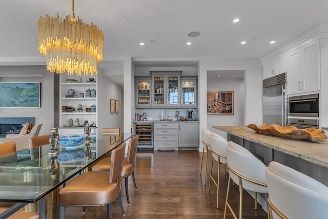 dining area with an inviting chandelier, dark hardwood / wood-style flooring, beverage cooler, and indoor bar