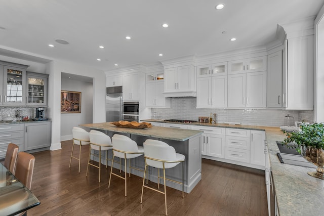 kitchen with a kitchen island, white cabinetry, appliances with stainless steel finishes, and light stone counters