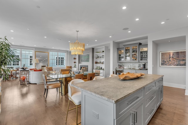 kitchen with gray cabinetry, hardwood / wood-style floors, decorative light fixtures, and a center island