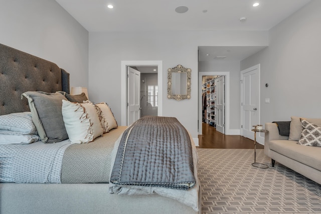 bedroom with a spacious closet and hardwood / wood-style flooring