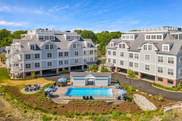 back of property with a community pool, an outdoor structure, and a patio area