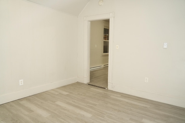 spare room with baseboard heating, lofted ceiling, and light hardwood / wood-style floors