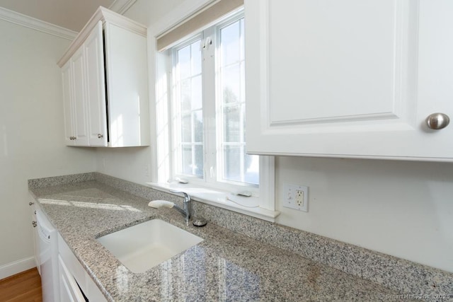 kitchen with white cabinetry, sink, ornamental molding, white dishwasher, and light stone counters