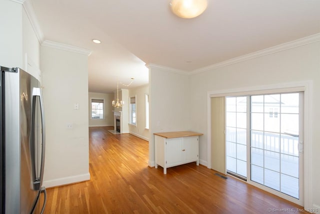 empty room with crown molding, an inviting chandelier, and light wood-type flooring