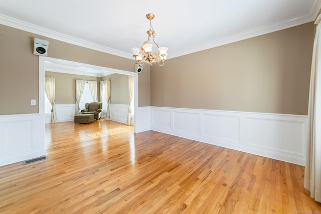 empty room featuring light wood-style flooring, crown molding, visible vents, and a notable chandelier