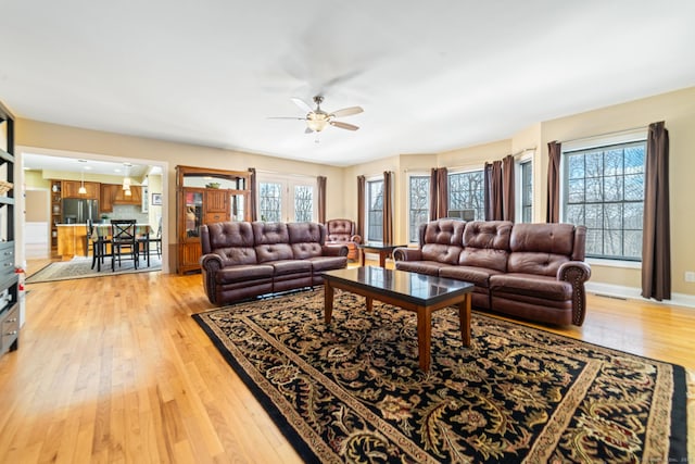 living room featuring a healthy amount of sunlight, light wood finished floors, ceiling fan, and baseboards