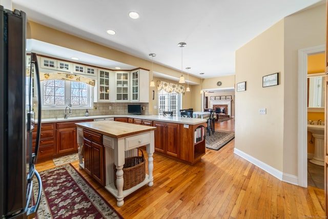 kitchen with decorative backsplash, light wood-style flooring, wood counters, freestanding refrigerator, and a peninsula