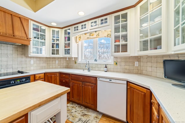 kitchen featuring tasteful backsplash, glass insert cabinets, a sink, dishwasher, and black electric cooktop