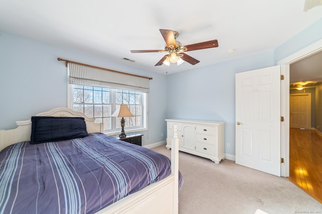 bedroom with light carpet, a ceiling fan, visible vents, and baseboards