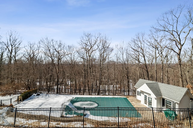 snow covered pool with a patio area, fence, a fenced in pool, and an outbuilding