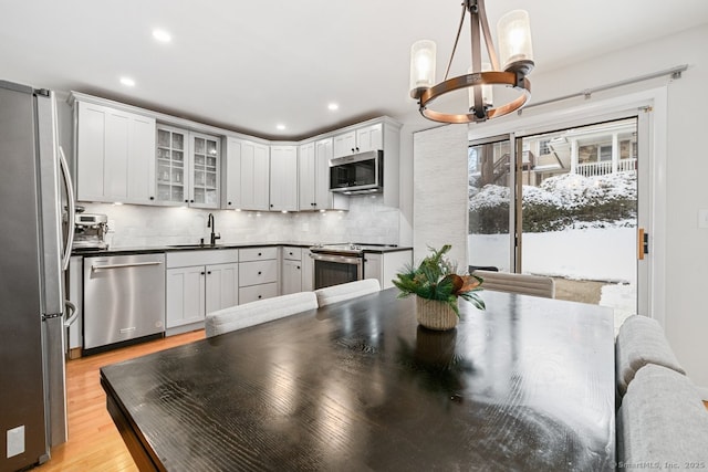 kitchen featuring pendant lighting, sink, stainless steel appliances, tasteful backsplash, and white cabinets