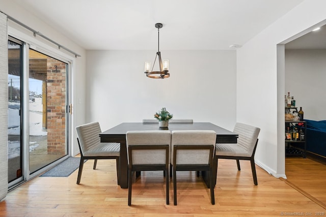 dining area with an inviting chandelier and light hardwood / wood-style flooring