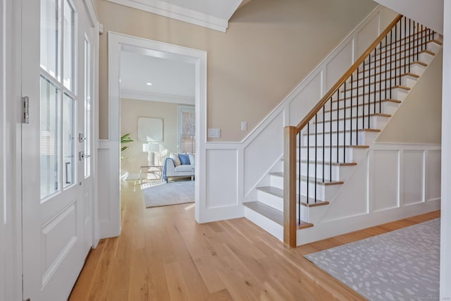 entrance foyer featuring ornamental molding and light hardwood / wood-style flooring