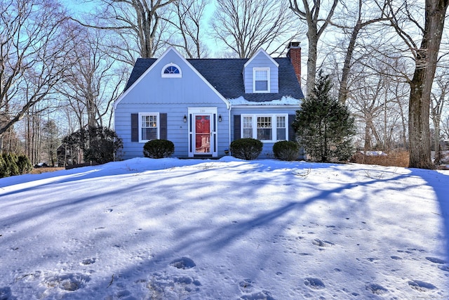 cape cod home with a shingled roof and a chimney