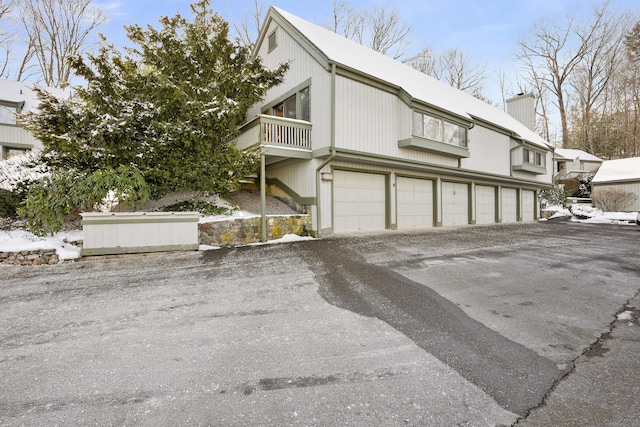 snow covered property featuring a garage and a balcony