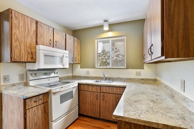 kitchen with dark wood-type flooring, white appliances, sink, and a textured ceiling