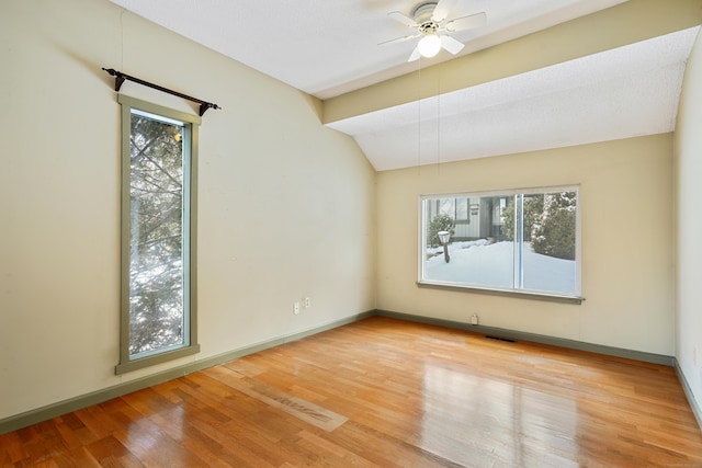 empty room with ceiling fan, lofted ceiling, hardwood / wood-style floors, and a textured ceiling