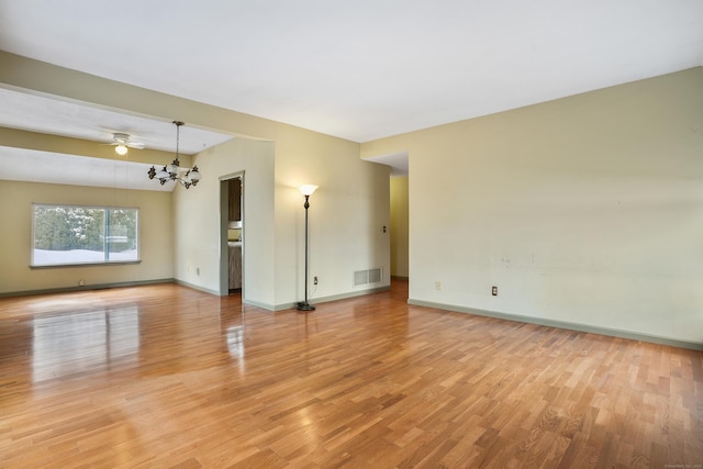 spare room with a notable chandelier and light wood-type flooring