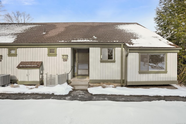 snow covered rear of property featuring central AC unit