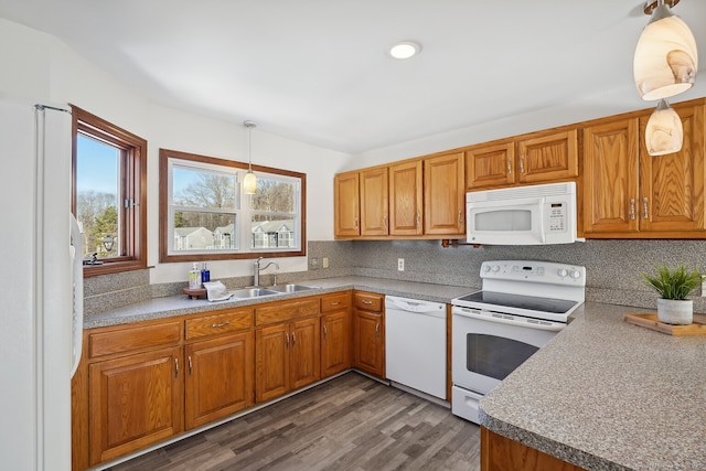 kitchen with white appliances, backsplash, a sink, and brown cabinetry