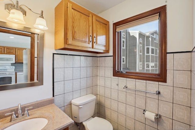 half bath with vanity, toilet, and tile walls