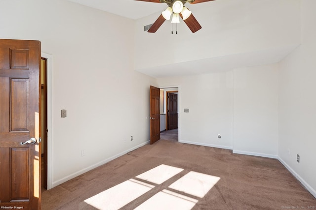 empty room with light carpet, ceiling fan, and baseboards