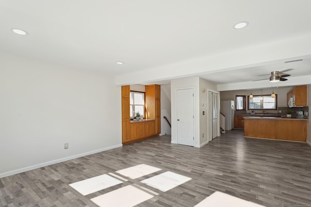 unfurnished living room with ceiling fan, recessed lighting, wood finished floors, and baseboards