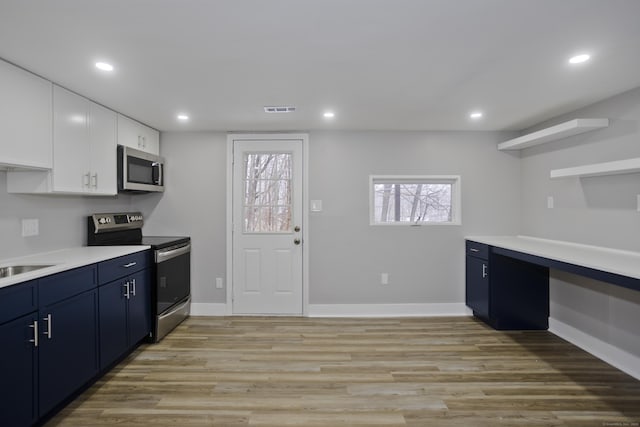 kitchen featuring blue cabinetry, sink, white cabinetry, light hardwood / wood-style flooring, and appliances with stainless steel finishes