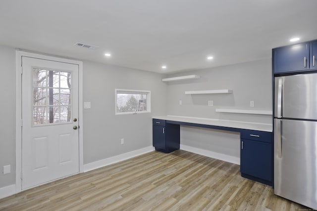 kitchen with blue cabinetry, built in desk, stainless steel fridge, and light hardwood / wood-style floors