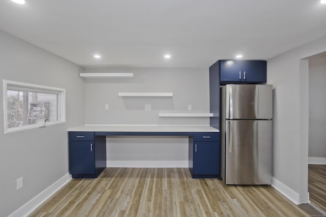 kitchen featuring stainless steel refrigerator, light hardwood / wood-style floors, built in desk, and blue cabinetry