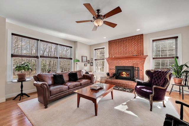 living room with a ceiling fan, wood finished floors, recessed lighting, baseboards, and a brick fireplace