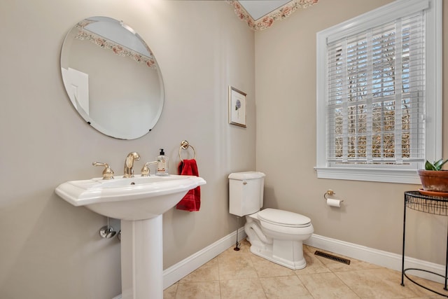 half bathroom with tile patterned floors, toilet, baseboards, and visible vents