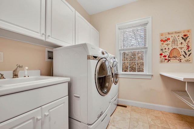 clothes washing area with a sink, cabinet space, separate washer and dryer, light tile patterned flooring, and baseboards