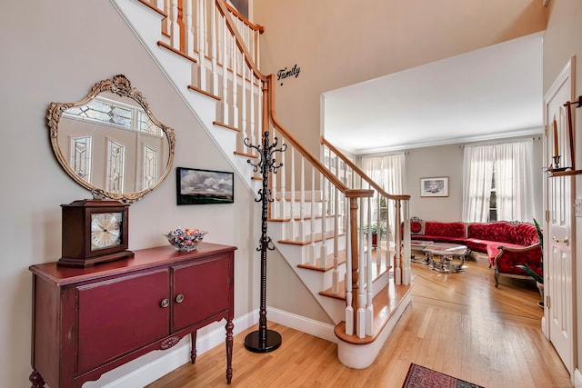 stairway featuring crown molding, wood finished floors, and baseboards