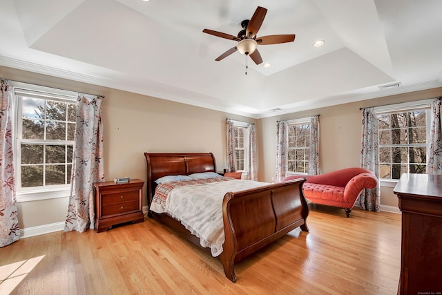 bedroom featuring visible vents, baseboards, light wood-type flooring, a tray ceiling, and recessed lighting