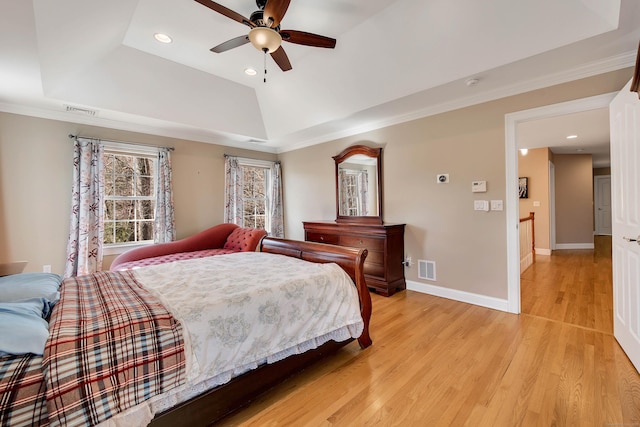 bedroom with visible vents, a raised ceiling, light wood-style floors, and baseboards