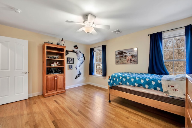 bedroom with a ceiling fan, light wood-style flooring, baseboards, and visible vents