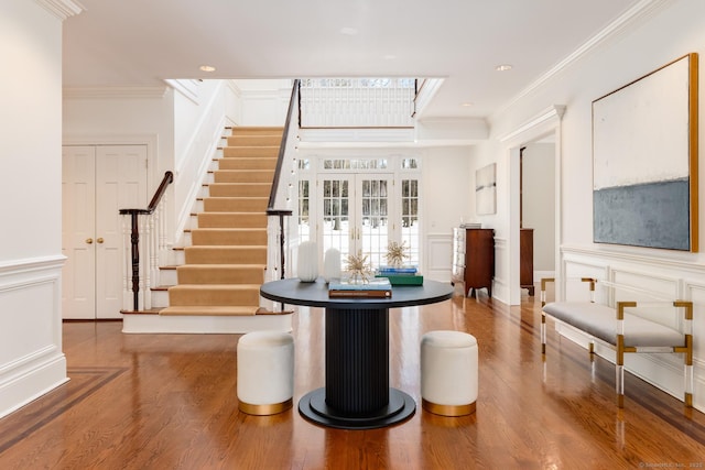 interior space featuring stairway, ornamental molding, a decorative wall, and french doors