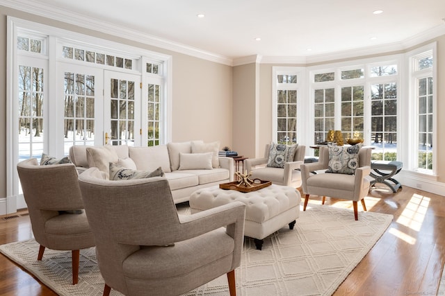 living area featuring ornamental molding, visible vents, and wood finished floors