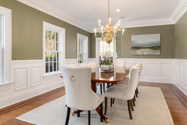 dining area featuring an inviting chandelier, ornamental molding, dark wood-type flooring, and wainscoting