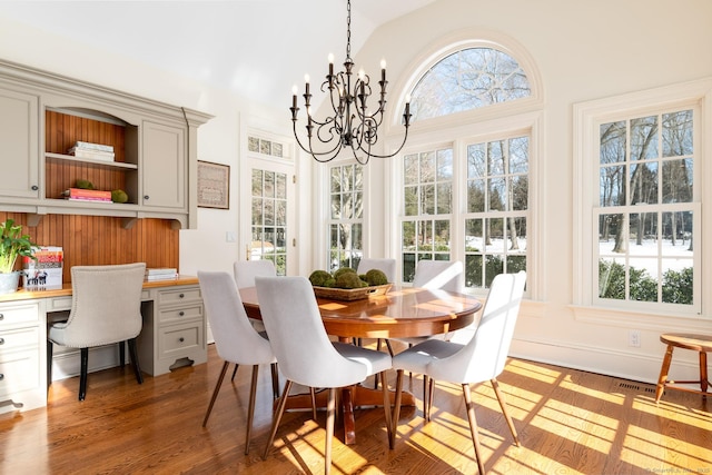 dining space featuring lofted ceiling, wood finished floors, built in study area, and a healthy amount of sunlight