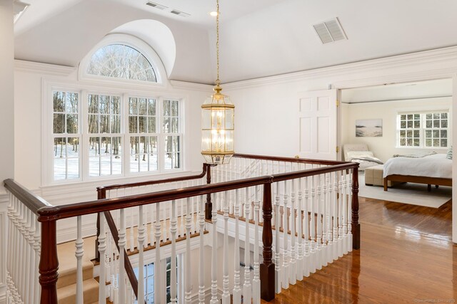 hallway featuring visible vents, vaulted ceiling, wood finished floors, and an upstairs landing